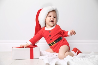 Cute little baby in Christmas costume with gift at home