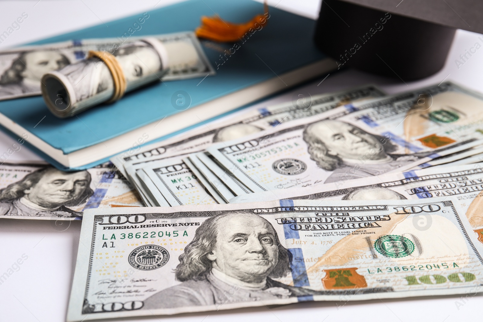 Photo of Dollars with student graduation hat and book on white background. Tuition fees concept