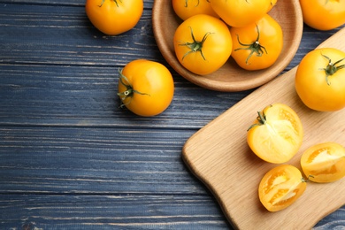 Photo of Ripe yellow tomatoes on blue wooden table, flat lay. Space for text