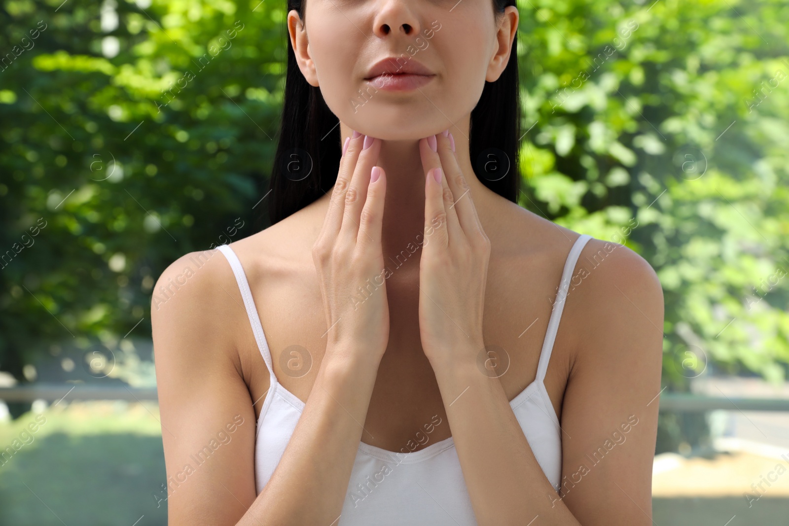 Photo of Young woman doing thyroid self examination near window, closeup