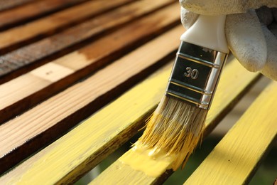 Worker painting wooden surface with yellow dye, closeup. Space for text