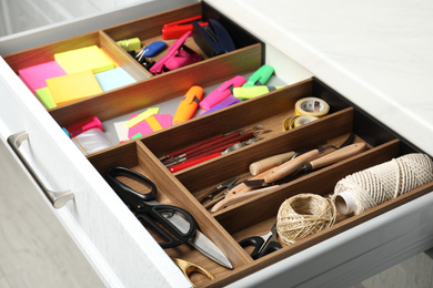 Sewing accessories and stationery in open desk drawer indoors