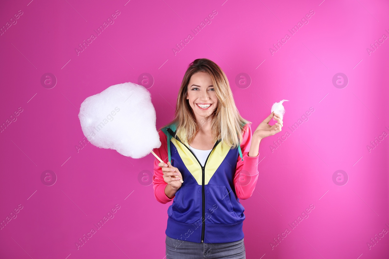 Photo of Young pretty woman with cotton candy on colorful background