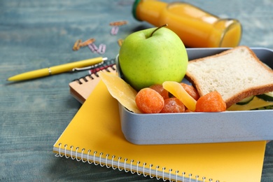 Photo of Lunch box with appetizing food and stationery on table