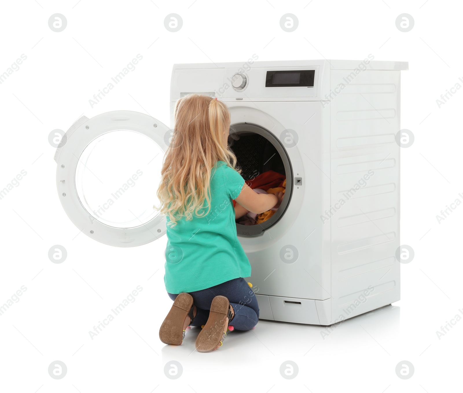 Photo of Cute little girl looking into washing machine with laundry on white background