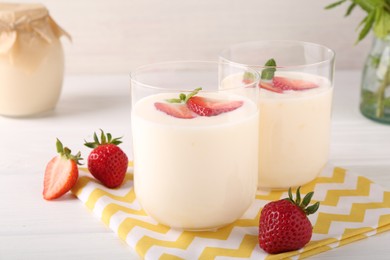Photo of Tasty yogurt and strawberries in glasses on white wooden table, closeup