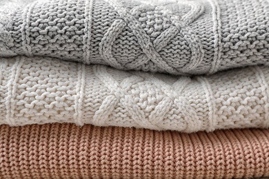 Photo of Stack of folded warm knitted sweaters, closeup