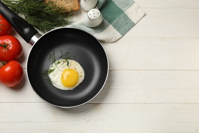 Photo of Delicious fried egg in frying pan on white wooden table, flat lay. Space for text