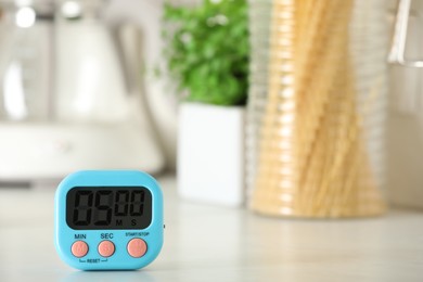 Photo of Digital kitchen timer on white table indoors. Space for text