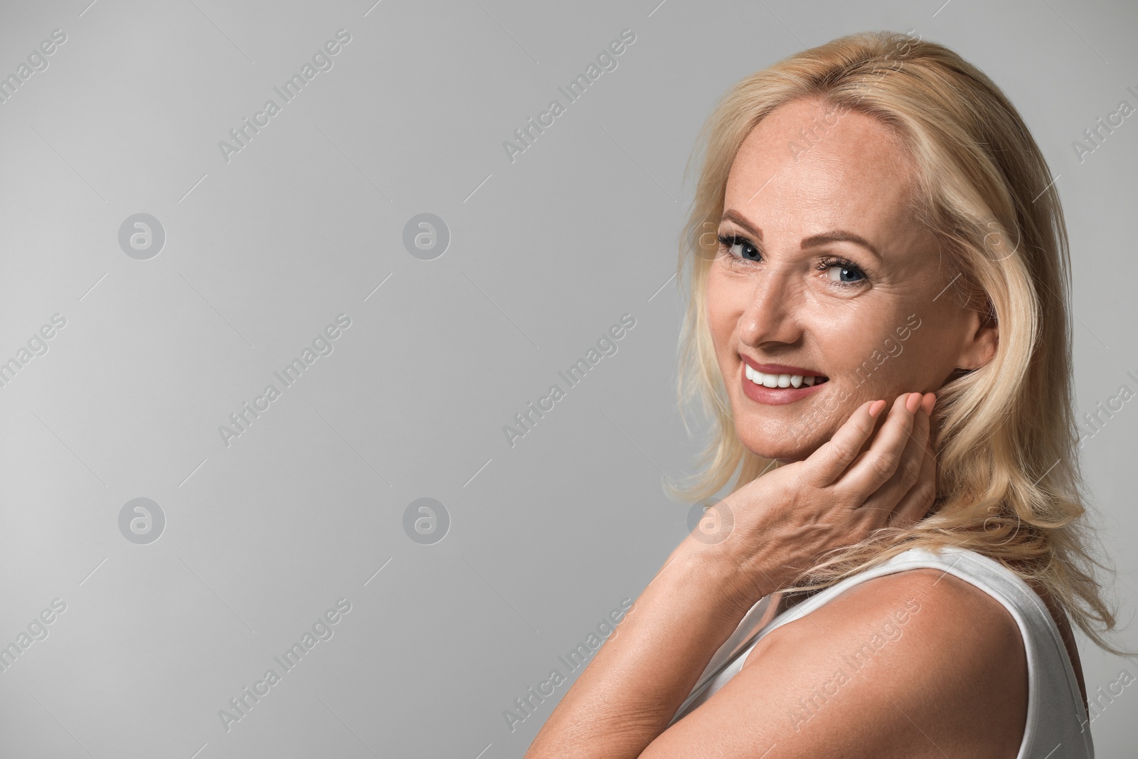 Photo of Portrait of beautiful mature woman with perfect skin on grey background. Space for text
