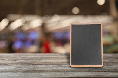 Blank small blackboard on wooden table in cafe, mockup for menu design 