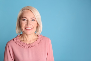 Photo of Portrait of charming mature woman with healthy beautiful face skin and natural makeup on blue background, space for text