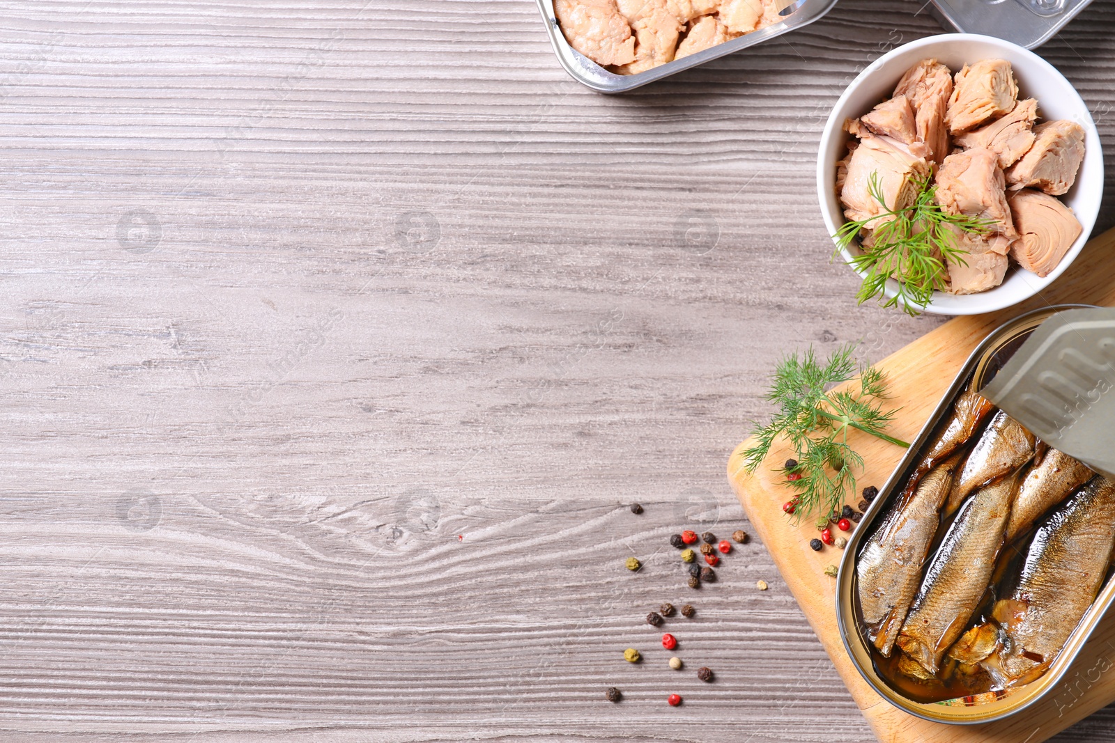 Photo of Flat lay composition with open tin can and fish meat on wooden table, space for text