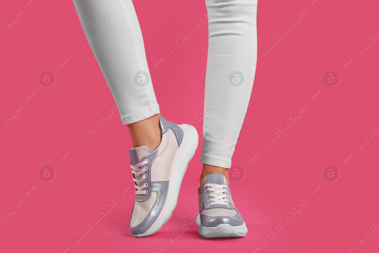 Photo of Woman wearing sneakers on pink background, closeup