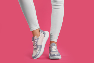 Photo of Woman wearing sneakers on pink background, closeup