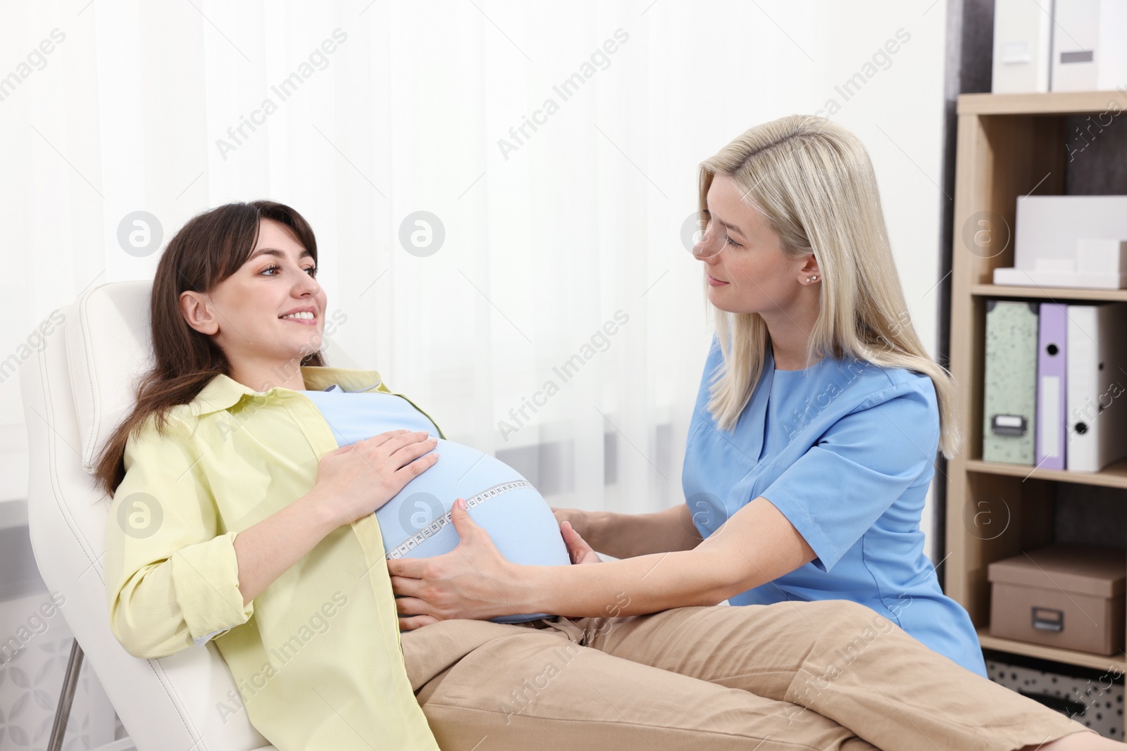 Photo of Pregnancy checkup. Doctor measuring patient's tummy in clinic