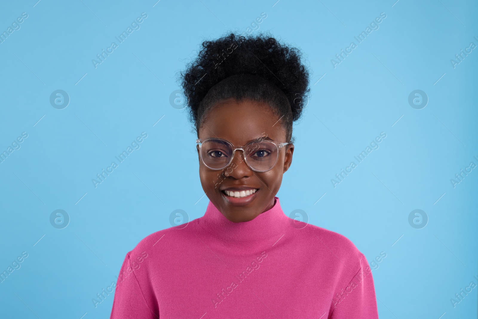 Photo of Portrait of beautiful young woman in eyeglasses on light blue background