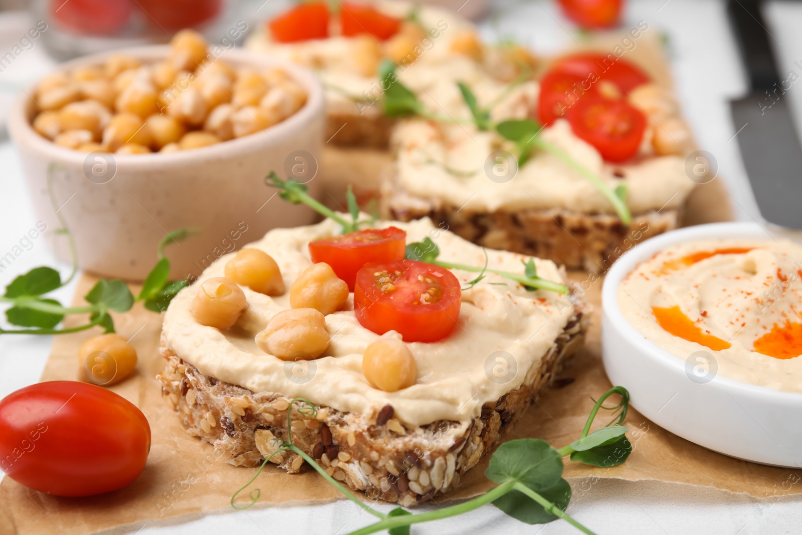 Photo of Delicious sandwiches with hummus and ingredients on wooden board, closeup