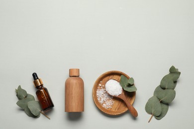 Photo of Aromatherapy products. Bottles of essential oil, sea salt and eucalyptus leaves on grey background, flat lay