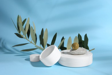 Jars of olive cream on light blue background. Cosmetic products