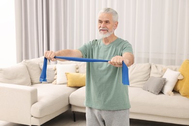 Senior man doing exercise with fitness elastic band at home