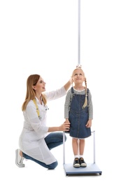 Photo of Doctor measuring little girl's height on white background