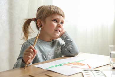 Cute little girl drawing at wooden table indoors. Child`s art