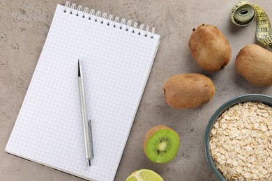 Photo of Healthy diet. Notebook, measuring tape, pen and products on grey table, flat lay