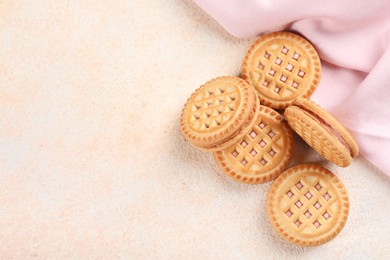 Photo of Tasty sandwich cookies with cream on beige background, flat lay. Space for text