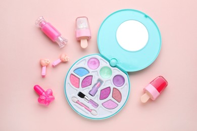 Photo of Eye shadow palette and other decorative cosmetics for kids on pink background, flat lay