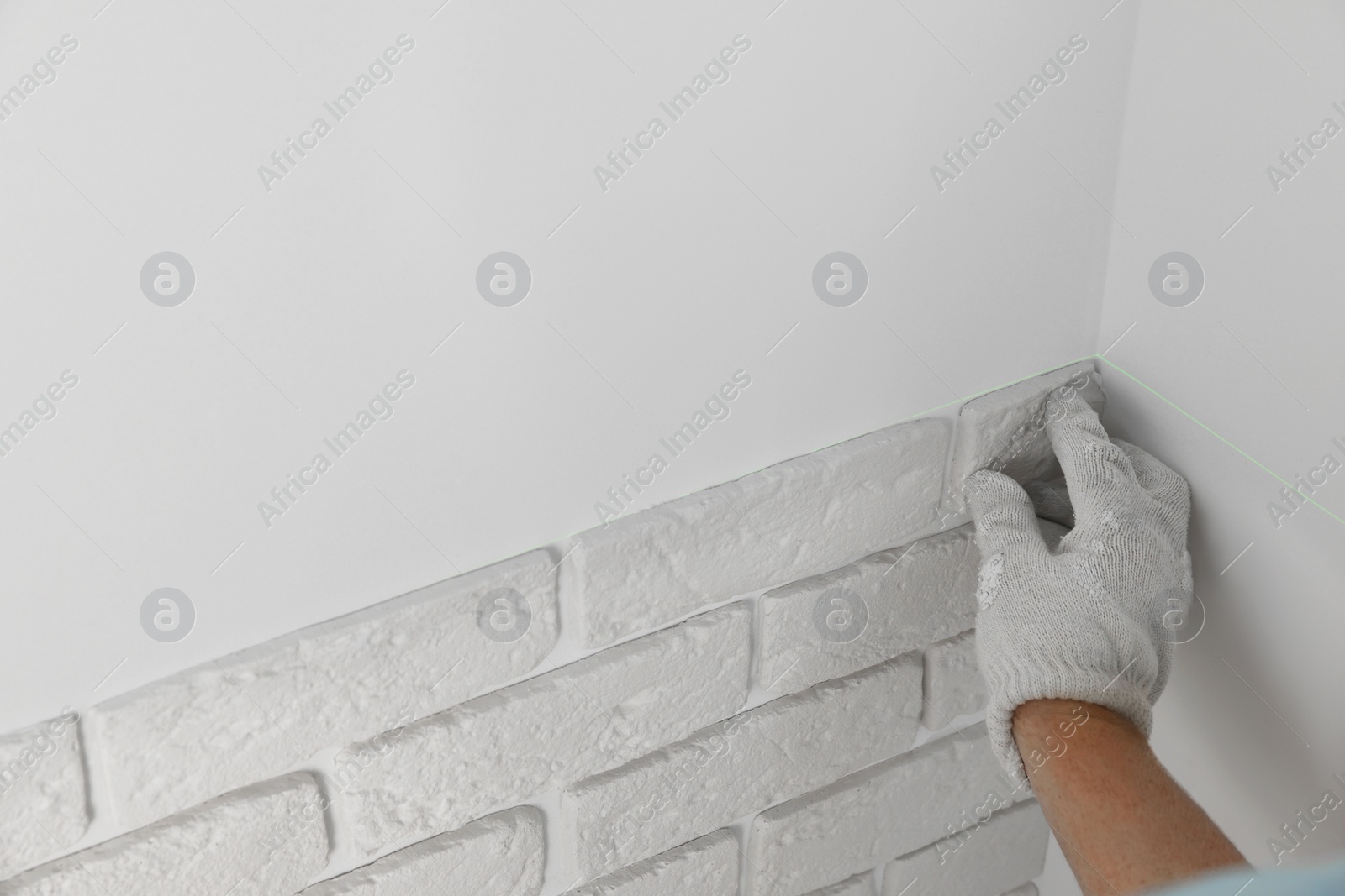 Photo of Worker installing decorative wall tiles in room, closeup