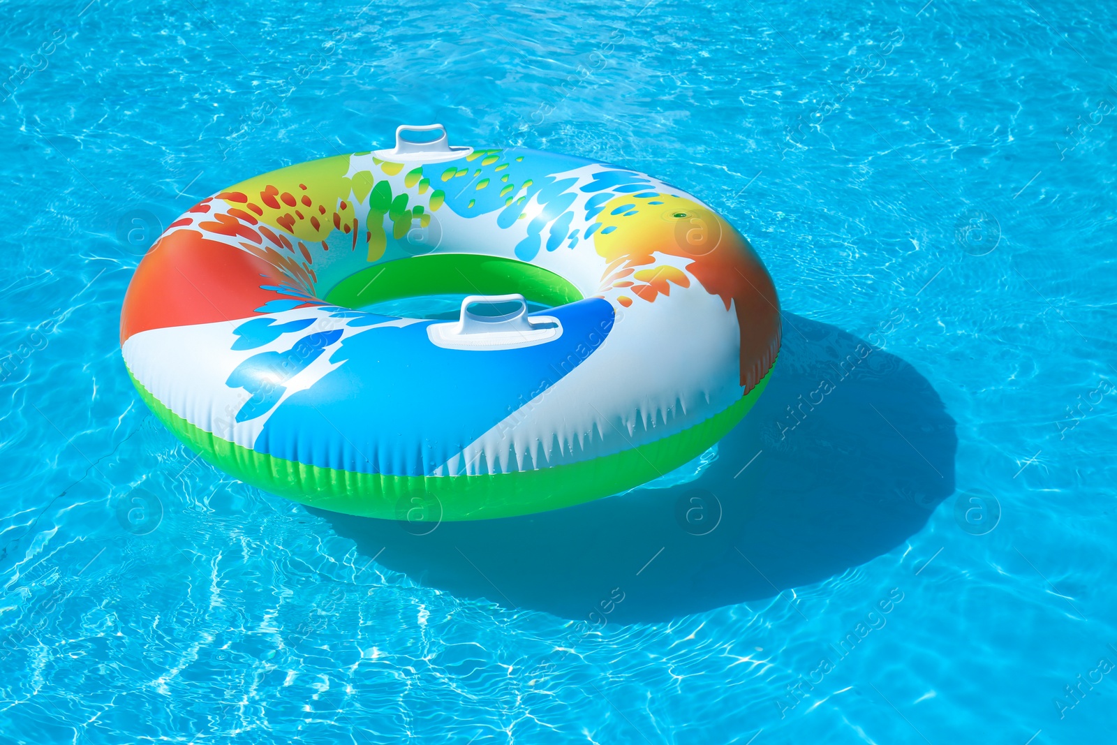 Photo of Colorful inflatable ring floating in swimming pool on sunny day