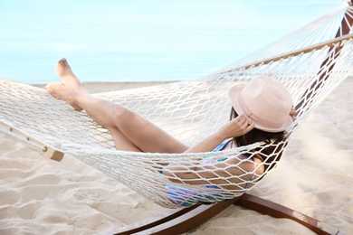 Photo of Young woman resting in hammock at seaside. Summer vacation