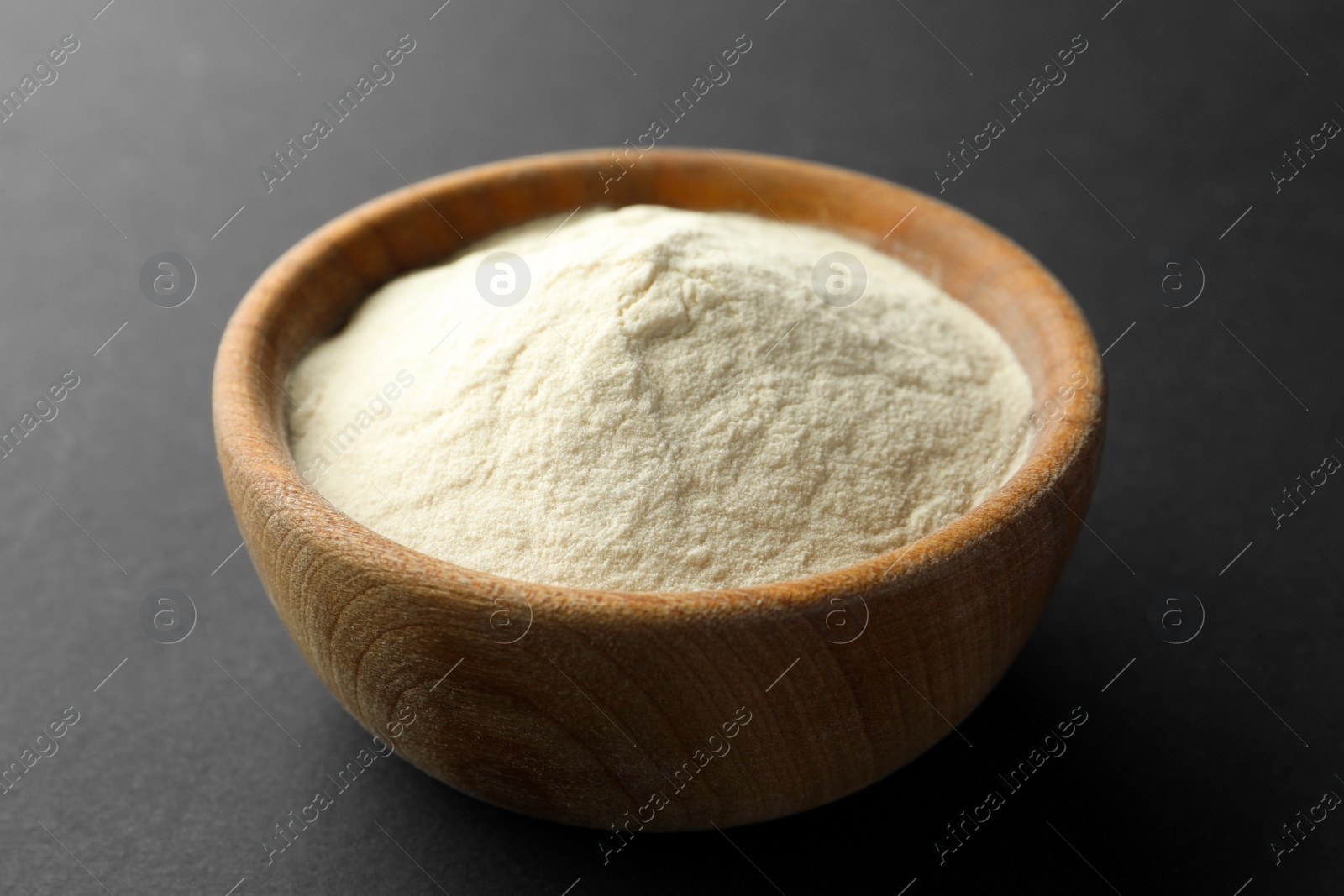 Photo of Bowl of agar-agar powder on black background, closeup