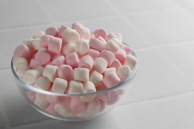 Photo of Glass bowl with delicious marshmallows on white table, closeup