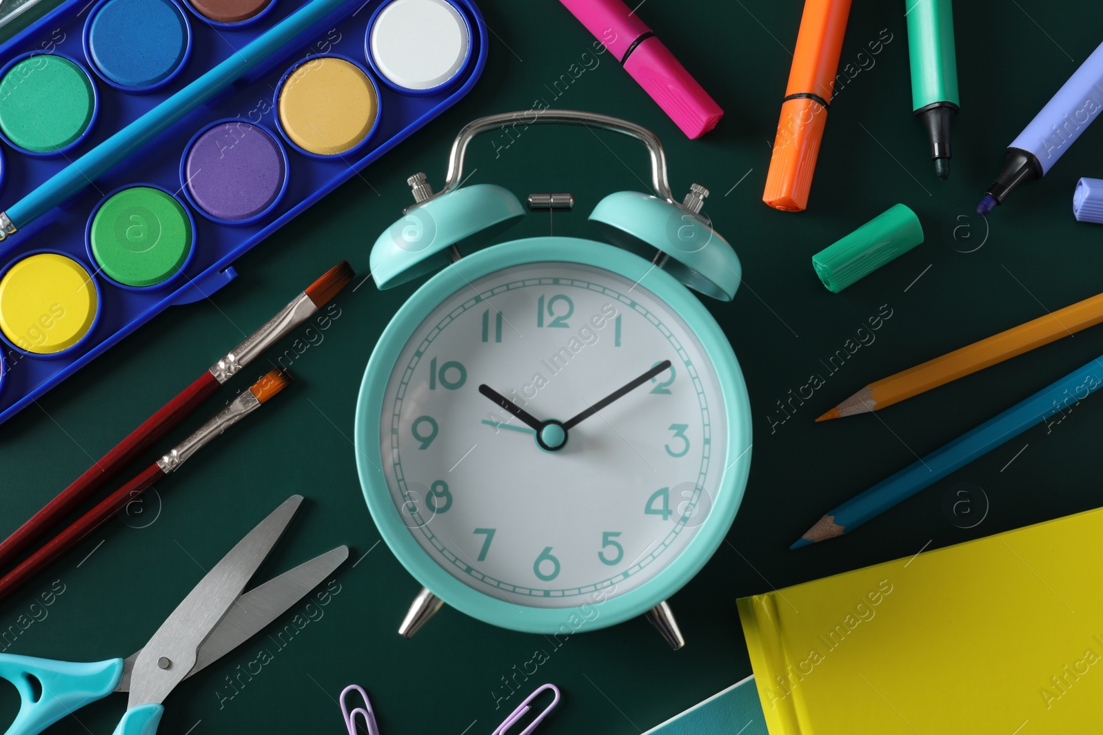 Photo of Flat lay composition with alarm clock and different stationery on green background. School time