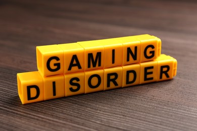 Photo of Phrase Gaming Disorder made of yellow cubes on wooden table, closeup