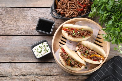 Delicious gua bao in bamboo steamer on wooden table, flat lay. Space for text