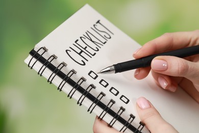 Woman filling Checklist against blurred background, closeup