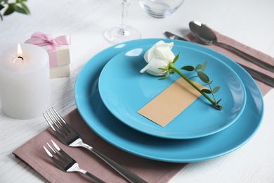 Photo of Elegant festive table setting with blank card on white wooden table