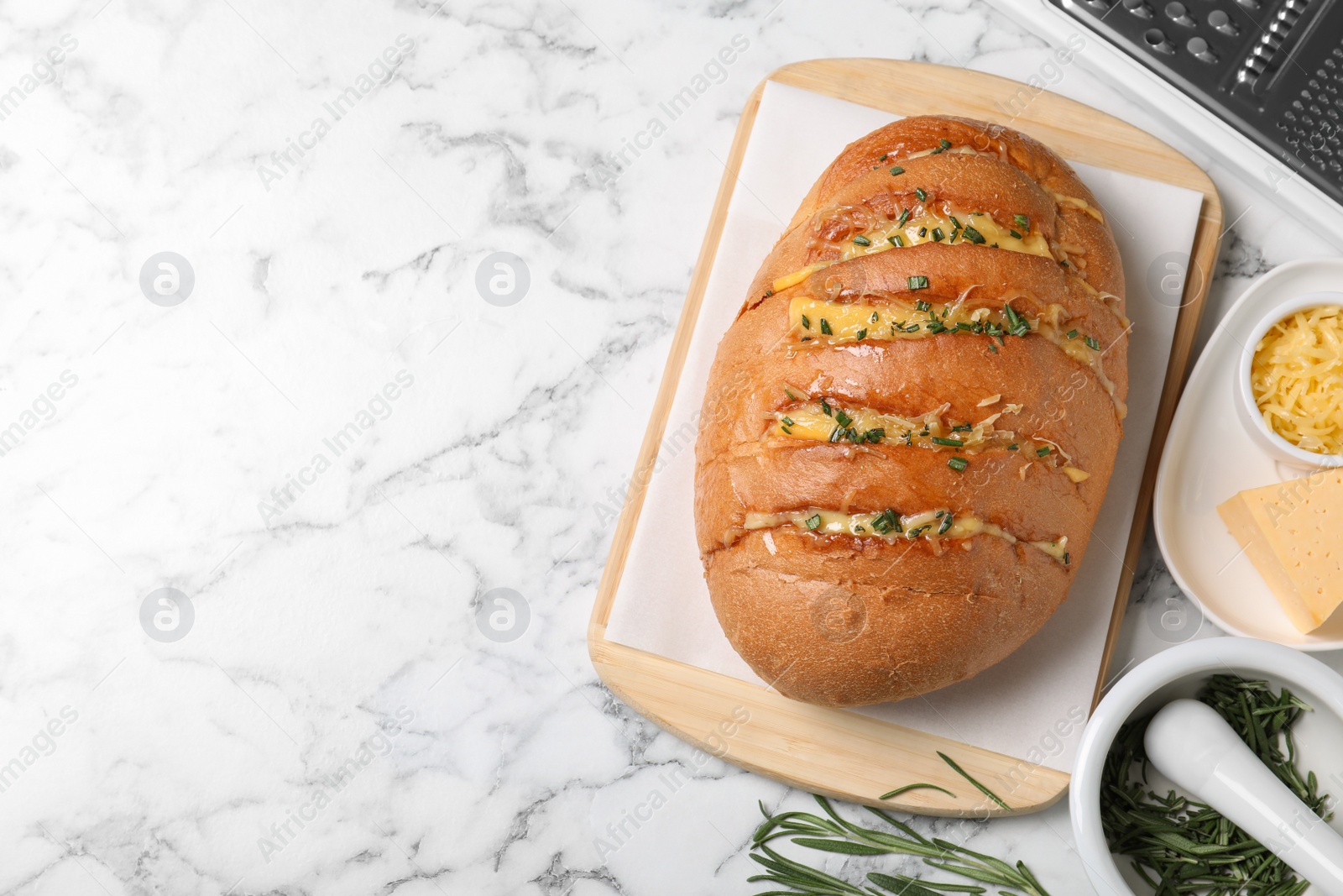 Photo of Delicious homemade garlic bread with herbs and cheese on white marble table, flat lay. Space for text