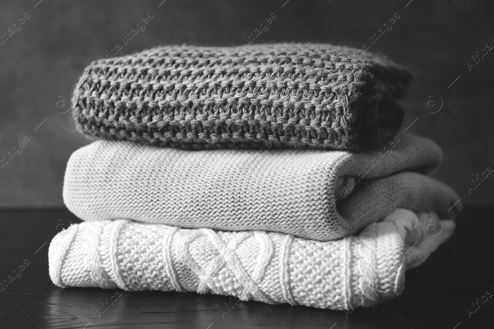 Photo of Stack of warm knitted clothes on table