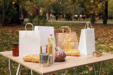 Photo of Volunteering. Different food products and paper bags on table in park