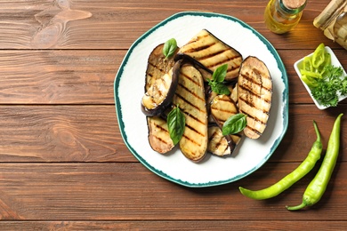 Photo of Plate with fried eggplant slices on wooden table, top view. Space for text