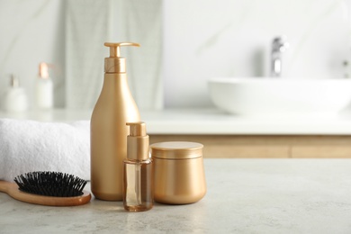 Photo of Different hair care products, towel and brush on table in bathroom. Space for text