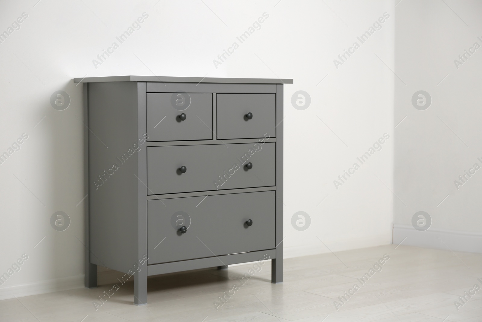 Photo of Grey chest of drawers near light wall