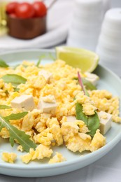 Photo of Delicious scrambled eggs with tofu and lime served on white table, closeup