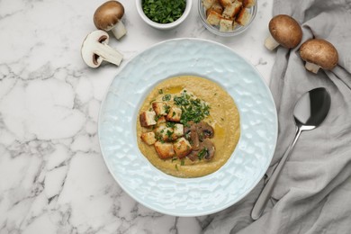 Delicious cream soup with mushrooms and croutons on white marble table, flat lay. Space for text