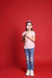 Photo of Cute girl in diadem with magic wand on red background. Little princess