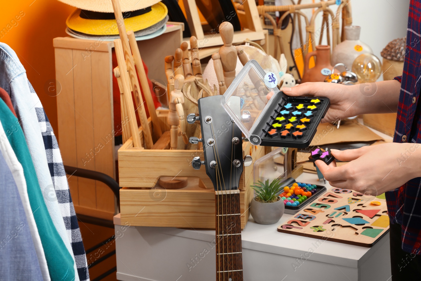 Photo of Woman holding smart game IQ near table with different stuff indoors, closeup. Garage sale